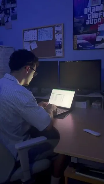 Vídeo vertical: chico trabajando con un portátil en su escritorio